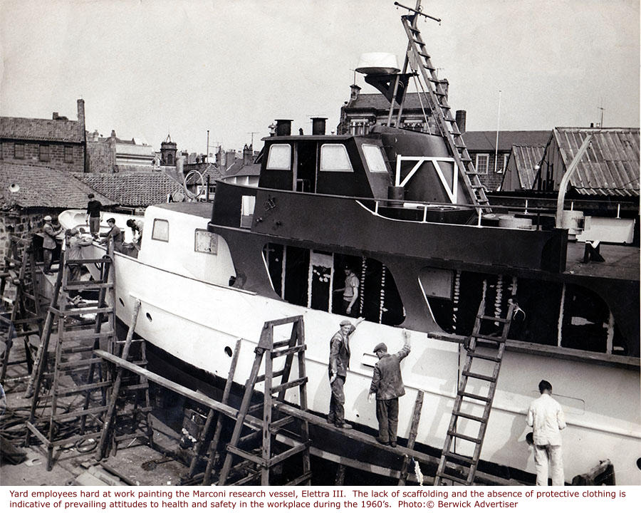 Yard employees hard at work painting the Marconi research vessel, Elettra III.  The lack of scaffolding and the absence of protective clothing is indicative of prevailing attitudes to health and safety in the workplace during the 1960’s.  Photo:© Berwick Advertiser